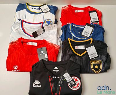 quatre maillots de foot posés sur une étagère, avec leurs étiquettes encore attachées
