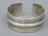 sterling silver cuff bracelet with engraved design on the outside of it