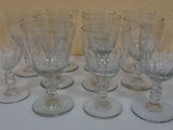 six empty wine glasses are lined up on a white table