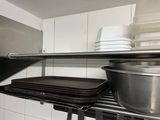 a metal shelf with pots and pans on it in a kitchen