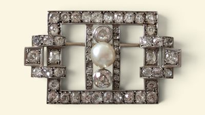 une image représentant une broche ornée de perles et de diamants sur fond blanc