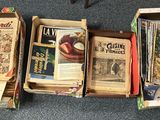 Plusieurs cartons de livres sont alignés en rangée sur le sol