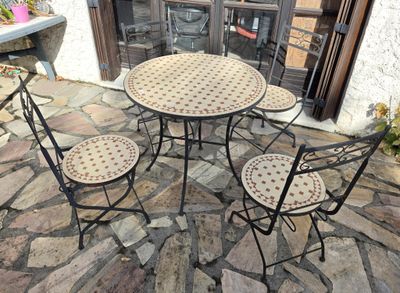 quatre chaises et une table sur une terrasse en pierre