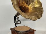 un vieux gramophone posé sur un socle en bois, avec un fond blanc