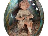 une figurine représentant un garçon assis dans un coquillage
