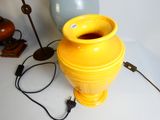 a yellow vase sitting on a table next to a lamp