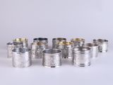 un ensemble composé de six tasses en argent et d'une cuillère en argent, posé sur une surface blanche
