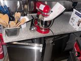 a kitchen with a red mixer and a silver dishwasher on the counter