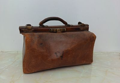 a brown leather suitcase sitting on a marble floor
