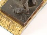 a bronze figurine of a man with a shoe on it