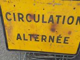 a yellow and black sign on the ground next to a red and white sign