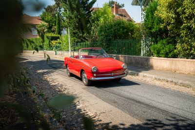 une voiture rouge qui roule dans la rue