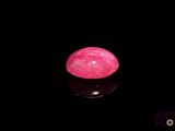a close up of a pink stone sitting on top of a black surface