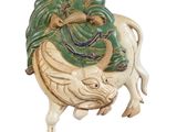 une figurine représentant un homme assis sur une vache