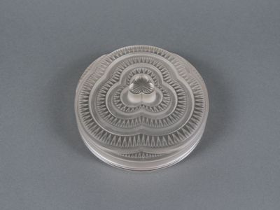 an antique silver plate with a bird on it on a gray surface