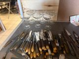 a lot of knives and wine glasses on the table