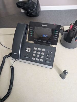 a telephone that is sitting on a desk next to a pen and pencil holder
