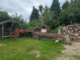 a pile of wood in the yard next to a tractor