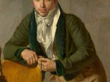 portrait of a man in a green jacket leaning on a yellow chair