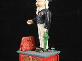 une statue représentant un homme avec une pipe et un chapeau, posée sur une boîte