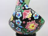 a black vase with colorful flowers on it on a clear base