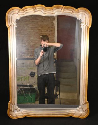 Miroir en bois sculpté argenté et doré à motif sinueux.