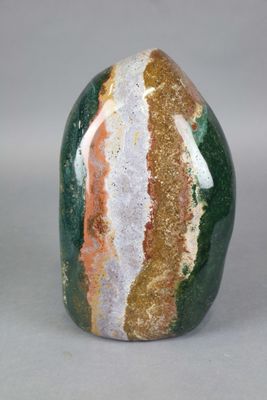 green, orange, and white striped rock on a gray surface