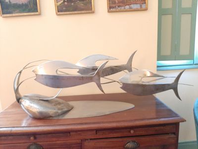 une sculpture métallique représentant un poisson posée sur une commode