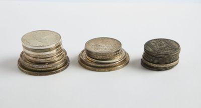 trois piles de pièces empilées les unes sur les autres sur une surface blanche