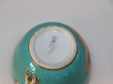 a small blue vase with a gold decoration on it