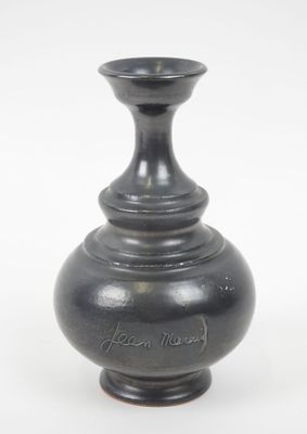 un vase noir posé sur une surface blanche