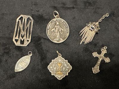 plusieurs breloques religieuses en métal argenté suspendues à un tissu noir
