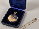 a gold pocket watch in a blue case with a gold chain