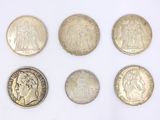 six different types of silver coins on a white surface