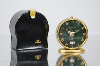 une petite horloge posée à côté d'une autre petite horloge sur une table