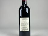 a bottle of red wine sitting on top of a white table