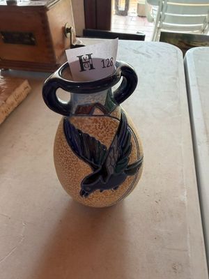 un vase avec un oiseau posé sur une table