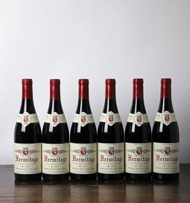 six bouteilles de vin rouge alignées sur une table en bois
