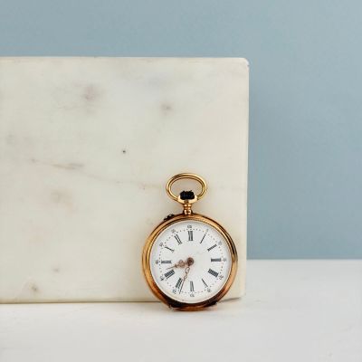 un bloc de marbre blanc sur lequel repose une montre de poche en or