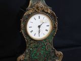 une petite horloge posée sur une surface noire