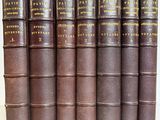 several old books are lined up on a white surface
