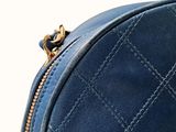 the back of a blue purse with a gold zipper on it