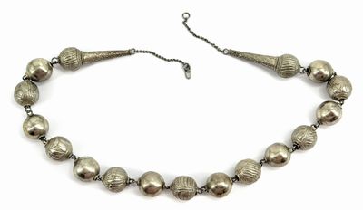 a close up of a necklace with silver beads on a white background