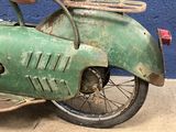 an old green motorcycle parked in front of a blue wall