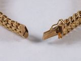 a close up of a gold chain bracelet on a white surface