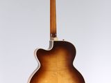 an acoustic guitar hanging from the back of a white wall