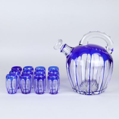 un pichet en verre violet avec six verres bleus et une cruche en verre