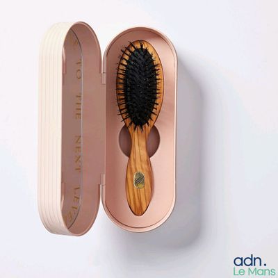 a wooden brush in a pink case on a white surface
