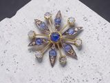 une image représentant une broche bleue et blanche posée sur une surface blanche
