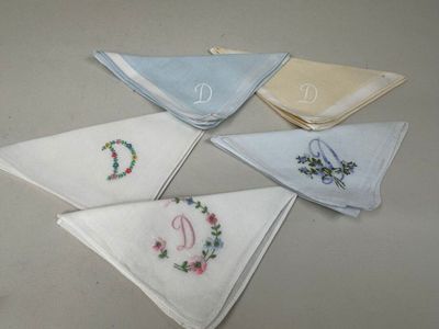 six mouchoirs ornés de monogrammes brodés, posés sur une table